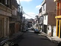 Photographie d'une rue. Des voitures sont stationnées à côté des trottoirs.