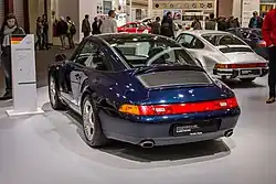 Porsche 993 Targa bleue, vue de 3/4 arrière. La plaque d'immatriculation indique "Porsche Classic Partner".