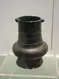 Pot, terre cuite noire, pâte fine tournée, poignée tubulaire. H. 15&nbsp;cm. Musée de Nanjing, province du Jiangsu.