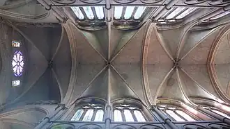 Vue couleur de la voûte de la nef d’une cathédrale en contre-plongée, aux travées divisées en six parties par trois ogives.