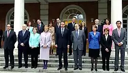 Des hommes et des femmes posant pour une photo de groupe sur des marches avec deux colonnes en fond.