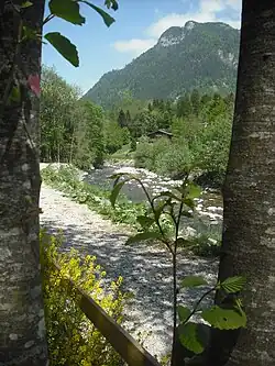 Promenade au bord du borne, Vue du Borne, au troisième plan un chalet et en arrière-plan une montagne.