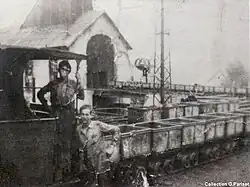 Série de wagonets de mine sortant d'un bâtiment.