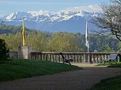 Photo d'un paysage montrant au premier plan un jardin public et au fond des montagnes enneigées.