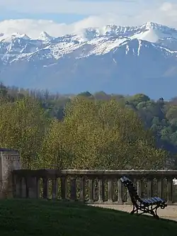 Photographie en couleurs d'un paysage de montagnes enneigées en arrière-plan d'une vallée boisée.