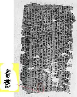 Photographie montrant une page d'un manuscrit écrit en caractères chinois. La page est très abîmée et est parsemée de trous de diverses tailles en bordure et au centre.