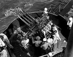 Photographie en plongée d'un affût quadruple autour duquel s'affairent plusieurs marins.