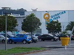 Photographie en couleurs d'un centre commercial et d'un parking.