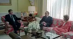 Une femme et deux hommes parlent ensemble, assis dans des canapés