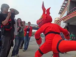 5 personnes caucasiennes à gauche, accompagnées d'une personne en costume de dragon rouge.