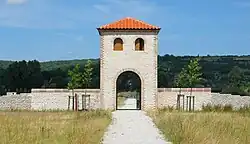 Vue d'un grand porche en plein cintre surmonté d'un étage à petites fenêtres.