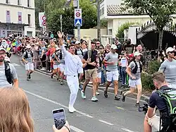 Relayeur de la flamme, en blanc, entouré des gardiens, en gris