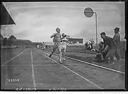 Photographie en noir et blanc d'un homme en tenue foncée de l'équipe de France portant le dossard no&nbsp;22. Il s'agit de René Wiriath. Il devance un homme en tenue blanche, représentant l'équipe d'Allemagne, portant le dossard no&nbsp;15