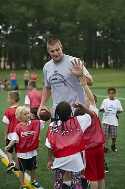 Un joueur de football américain entraîne des jeunes enfants et tape dans la main de l’un d'entre eux.