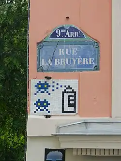 Mosaïque d'Invader sous une plaque de la rue.