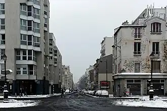 La rue vue depuis l'entrée principale du Père-Lachaise, sous la neige.