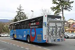 Photographie en couleurs d’un autocar bleu, blanc et noir vu de derrière, avec un porte-vélos à l’arrière.