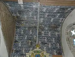 Photographie d'une voûte lambrissée peinte en bleu foncé, avec des angelots portant des chapelets