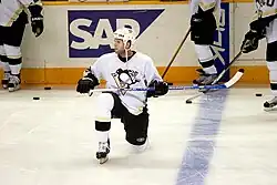 Photo de Ryan Whitney un genou sur la glace.
