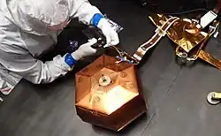 Photo d'un technicien en salle blanche travaille sur l'enceinte de SEIS.