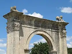 Photographie en couleurs de la partie supérieure d'un arc romain.