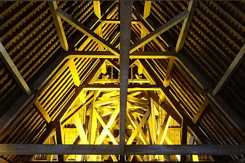 Charpente en bois éclairée par des lampes.