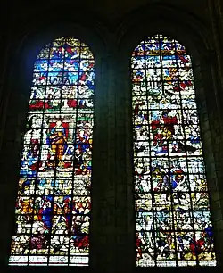 Deux grandes verrières colorées avec de nombreux personnages et un décor foisonnant. La partie centrale de chacune des verrières est occupée par une femme richement habillée.