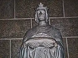 Statue de bronze d'un roi portant une relique sur un coussin.