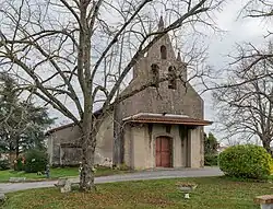 Photo de l'église Saint-Pierre. Vue de la porte d'entrée, située sur le clocher-mur et protégé par un porche. L'édifice est une église à nef unique.