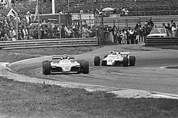 Photo en noir et blanc de deux monoplaces sur un circuit.
