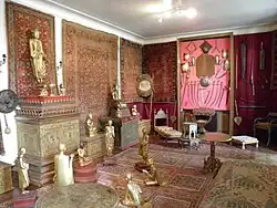 Pièce décorée de tapis aux murs et sur le sol, avec statues de bouddhas