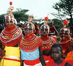 Photographie d'un groupe de jeunes filles portant de nombreux colliers et des vêtements de couleurs vives
