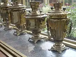 Une rangée de samovars cuivrés devant une fenêtre.