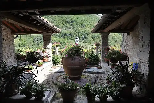 Cour végétalisée encadrée de colonnes et ouvrant sur un paysage de moyenne montagne.