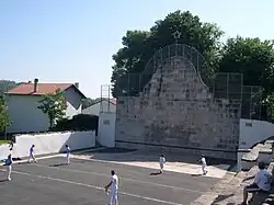 Photographie d’un fronton de pierres sur lequel s’affrontent au chistera six joueurs.