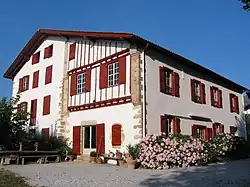 vue de trois quarts d'une maison à deux étages aux pans de bois rouge.