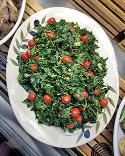 Plat contenant un sauté de chou kale agrémenté de tomates cerises.