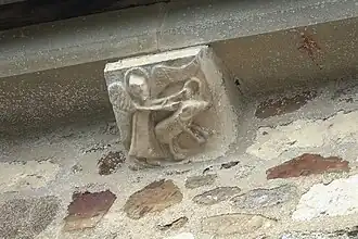 Un ange tenant avec la main droite un animal (un porc ?) par l'oreille et de la main gauche un anneau.