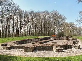 Photographie en couleurs d'un bâtiment religieux en ruine entouré d'arbres