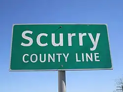 Panneau de signalisation routière, vert sur fond blanc, avec inscription Scurry county line.