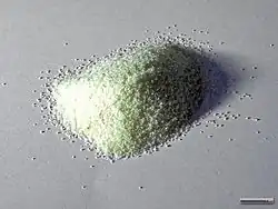 Un tas de grains de semoule, aussi appelée schemoul (spécialité juive, couleur blanc jaune, chaque grain faisant moins de 1 millimètre, sur un fond gris.