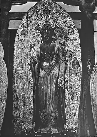 Yakushi Nyorai, dit Shaka Nyorai debout. Fin IXe&nbsp;siècle. Bois peint, H. 2,38&nbsp;m. Murō-ji, Nara.