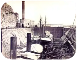 photographie de deux navires à vapeur en cale sèche avec un bâtiment abritant le moteur pour faire fonctionner les portes de l'écluse en arrière-plan