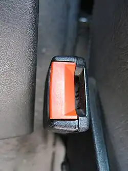 Gros plan sur le boîtier d'une ceinture de sécurité, reconnaissable à son bouton rouge