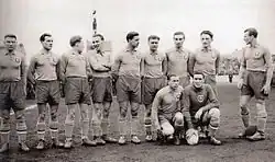 Photographie en noir et blanc de joueurs de football, alignés, vus de trois-quarts.