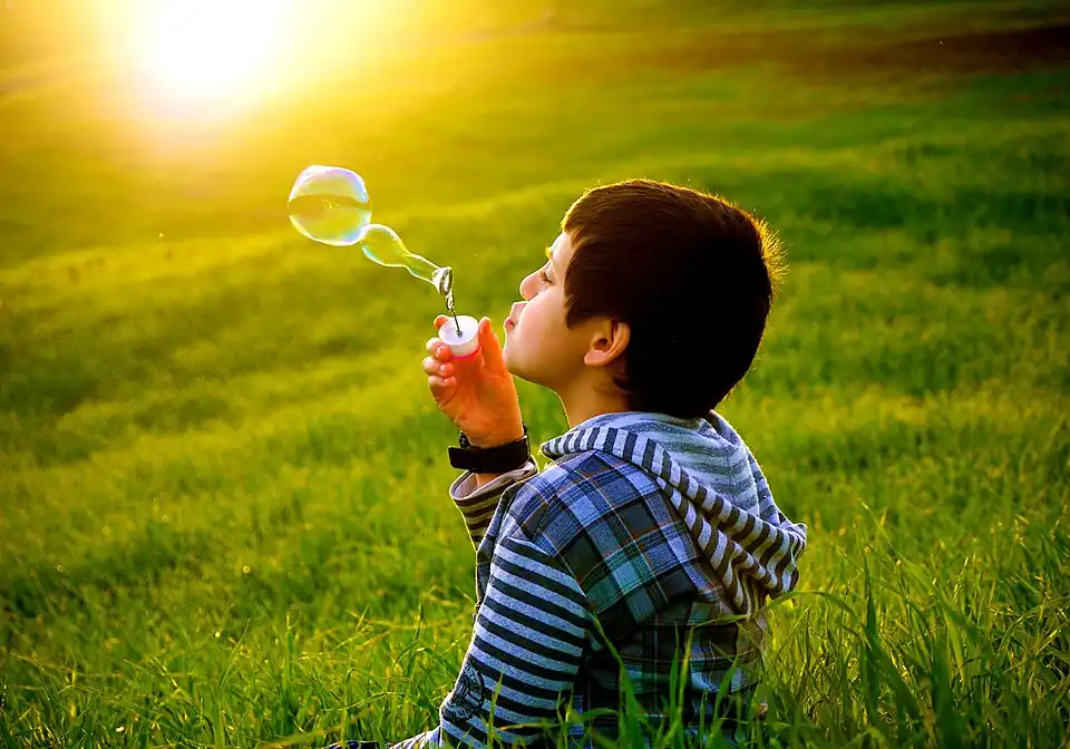 Un petit garçon faisant des bulles de savon dans une prairie d'Algérie