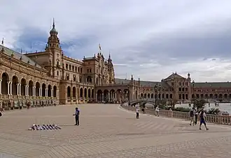 Place bordée de bâtiments d'architecture gothique et mudéjar, avec de nombreuses colonnes et arches.