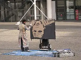 Artiste peignant un portrait à l'envers sur la place.