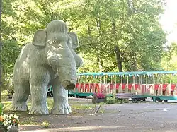 Photographie d'une statue de mammouth devant un petit train.