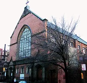 Façade d'église de style néo-gothique en briques rouges, parements en pierre